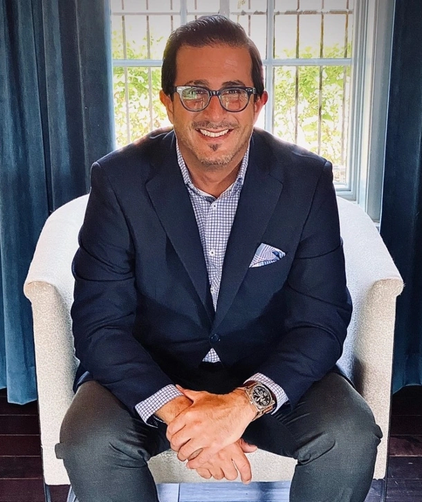 Charlie Barone sitting on a chair, in a suit